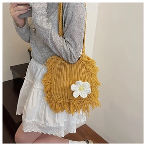 Detail of yellow knit shoulder bag with handmade crochet flower and fringe accents