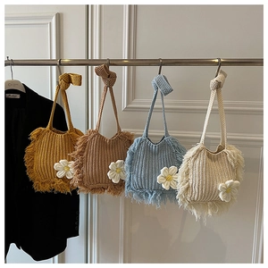 Close-up of knit crossbody bags with white daisy embroidery and long decorative fringe