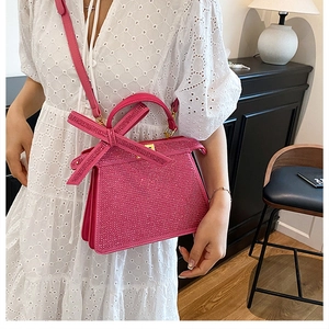 Détail du sac à main rose fuchsia avec strass, grand nœud et texture brillante élégante
