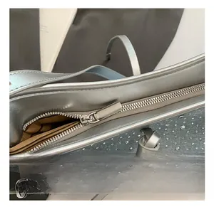 Dettaglio della cerniera argentata e degli strass scintillanti sulla borsa a tracolla in denim