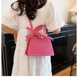 Détail du sac à main fuchsia en strass avec nœud en cristal porté sur modèle