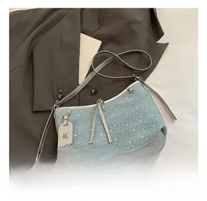 Dettaglio borsa in denim azzurro con borchie argentate e tracolla in pelle grigia