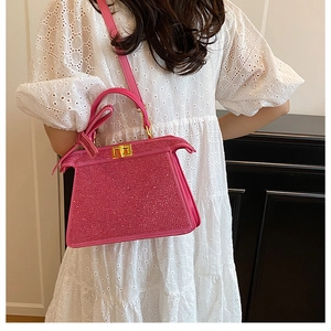Vue détaillée d'un sac à main strass rose avec fermoir rotatif doré élégant et bandoulière