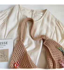 Detail of a brown crochet tote bag showing hollow knit patterns and colorful ring charms