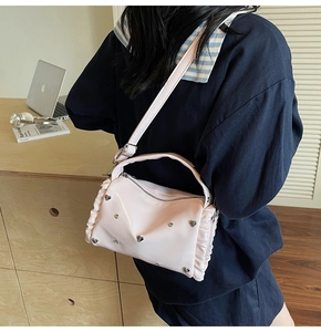 Detail of pink ruffled crossbody bag with heart stud and adjustable shoulder strap
