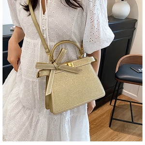 Détail d'un sac à main tissé doré champagne avec un grand nœud et fermoir doré