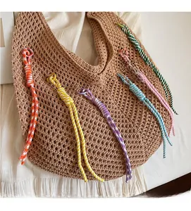 Detail of bohemian hollow knit tote with colorful hanging tassels on white fabric