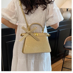 Détail du sac à main en strass doré champagne avec poignée à nœud papillon