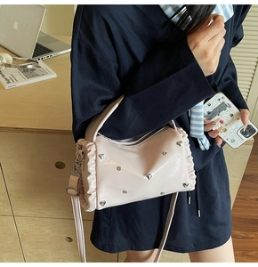 Pink pillow bag with heart rivets, ruffles, and detachable strap on a wooden desk