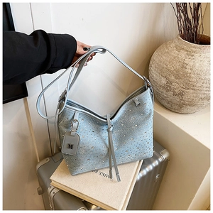Dettaglio della borsa a secchiello in denim celeste con strass e ciondolo a M in metallo