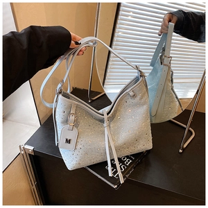 Dettaglio della borsa a secchiello in denim azzurro con strass luccicanti e ciondolo a M