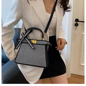 Détail du sac à main noir à strass avec nœud en cristal sur mannequin en blazer blanc
