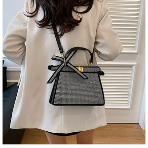 Détail d'un sac à main noir orné de strass argentés brillants et d'un grand nœud décoratif