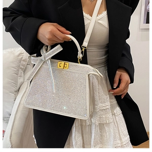 Détail du sac à main blanc orné de strass avec fermoir doré et nœud en cristal étincelant