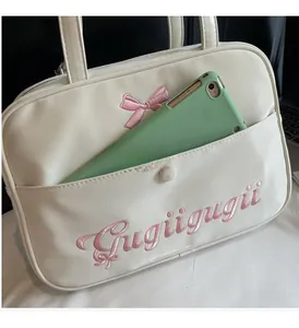 Close-up of a white tote bag featuring pink bow embroidery and a tablet in the front pocket