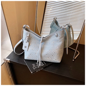 Dettaglio della borsa a secchiello in denim azzurro con strass e ciondolo a forma di M