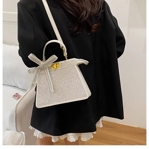 Détail d'un sac à main blanc orné de strass avec breloque nœud porté par un mannequin