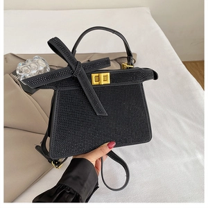 Détail d'un sac à main noir en strass avec fermoir doré et poignée supérieure