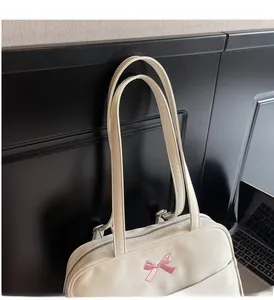 Detail showing white tote bag with pink bow embroidery and sturdy shoulder straps