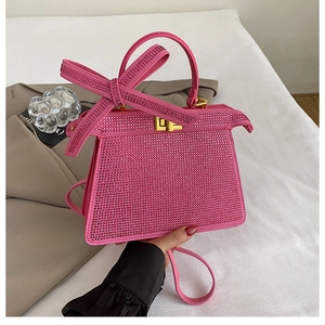 Détail du sac à main en strass rose avec un grand nœud étincelant et un fermoir doré