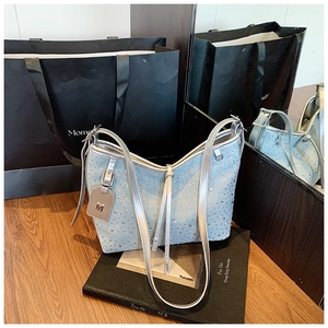 Dettaglio della borsa in denim con strass scintillanti e ciondolo metallico a forma di M