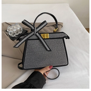 Gros plan du sac à main argenté en strass avec un grand nœud brillant et fermoir doré
