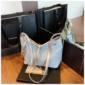 Dettaglio della borsa a spalla in denim azzurro con strass argentati e ciondolo a M