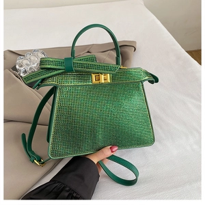 Détail d'un sac à main vert émeraude avec strass étincelants et fermoir en métal doré