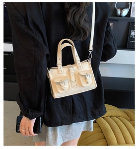 Detail view of beige biker style handbag with pockets and adjustable shoulder strap