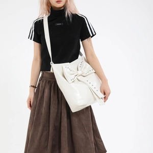 White glossy leather tote bag with a large rivet bow on the shoulder strap