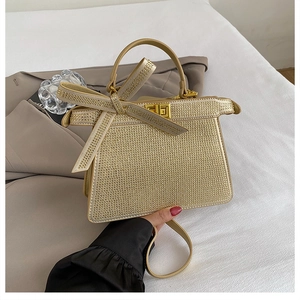 Vue détaillée d'un sac à main doré avec strass et nœud sur une literie blanche