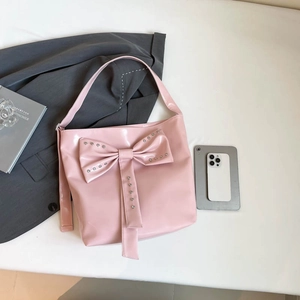 Pink patent leather tote bag featuring a large bow and metallic stud decorations
