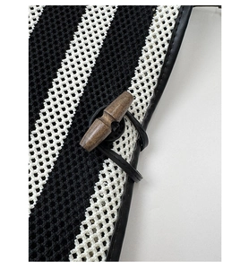 Detail of woven striped tote bag featuring mesh fabric and a wooden toggle button closure