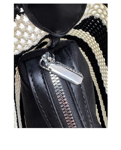Detailed close-up of the silver metal zipper and woven black and white shoulder strap