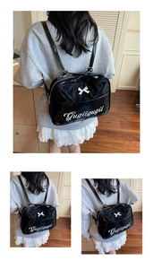 Detail of glossy black tote bag featuring a white 3D bow and Gugiigugii script logo