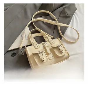 Close-up of cream white crossbody bag with lychee texture and silver buckles details