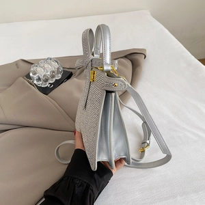 Détail du sac à main argenté avec strass, nœud décoratif et structure latérale en accordéon