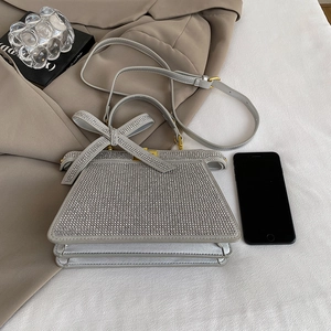 Détail d'un sac à main en strass avec nœud décoratif sur un blazer beige