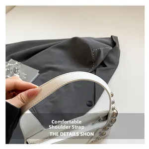 Detail of white leather bag featuring a wide comfortable strap and silver metal studs