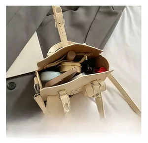 Detail view of the spacious inner compartment with zip pocket for cream leather handbag