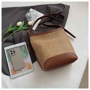 Detail of straw bucket bag with brown leather trim and base on an elegant aesthetic background