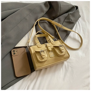 Detailed close-up of yellow lychee texture faux leather handbag with buckle pockets and strap