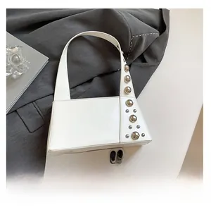 Detail view of white leather shoulder bag featuring unique silver rivet side decorations