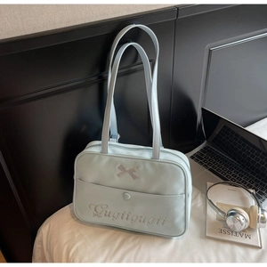 Close-up of light blue tote bag with ribbon detail and front pocket on a white bed