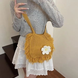 Handmade yellow knit crossbody bag with white flower charm and bohemian fringe details