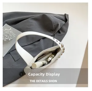 Top view of white leather shoulder bag interior showing daily essentials and silver studs