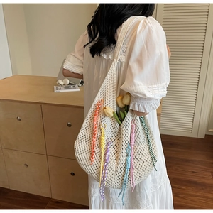Detail of bohemian knit tote bag with vibrant long tassels and hollow crochet texture