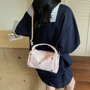Pink pillow bag with silver heart studs and ruffled edges shown as a crossbody
