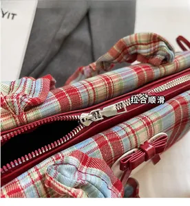 Detail of red zipper and decorative bow on a vintage plaid patterned shoulder bag