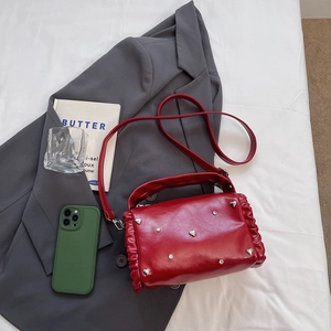 Red leather pillow bag with silver heart studs and ruffled edges, cross-body handle style